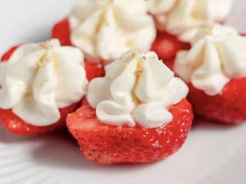 several deviled strawberries with cream cheese filling on a plate.